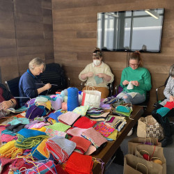 A group of people knitting squares for blankets