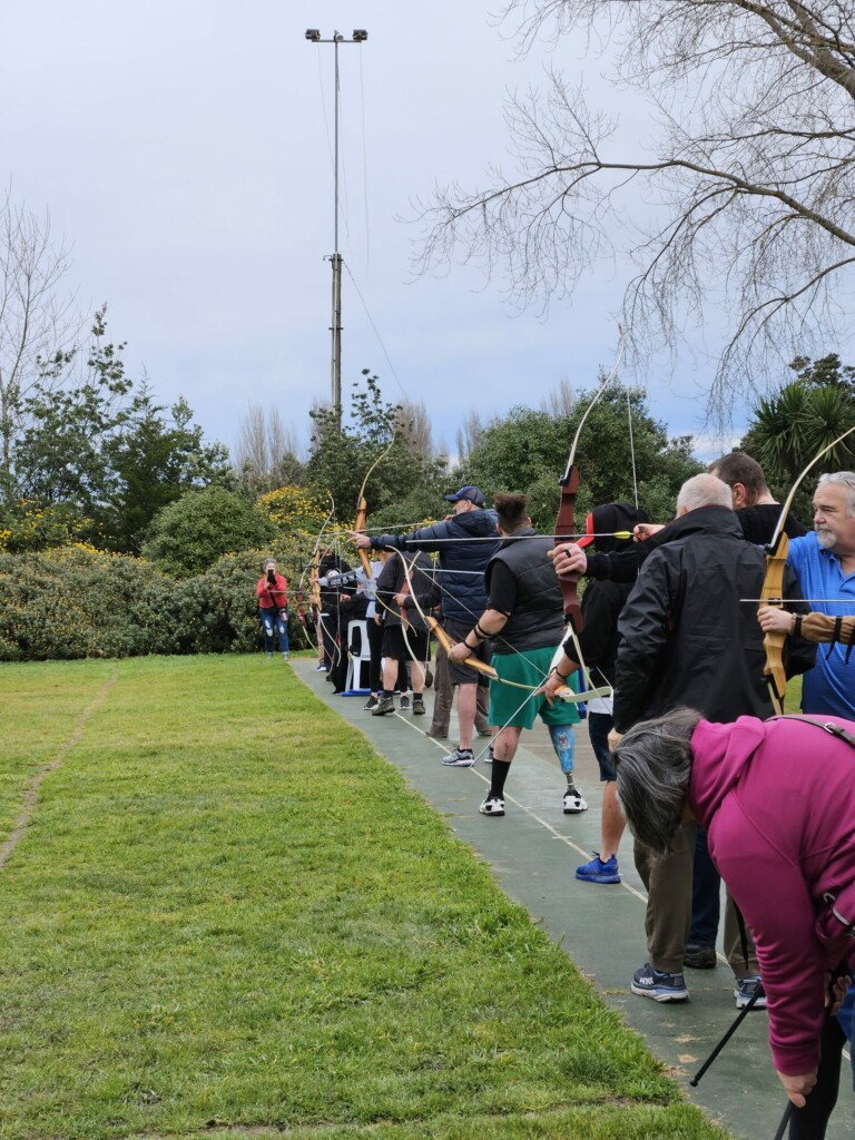 A photo of several people lined up and for archery