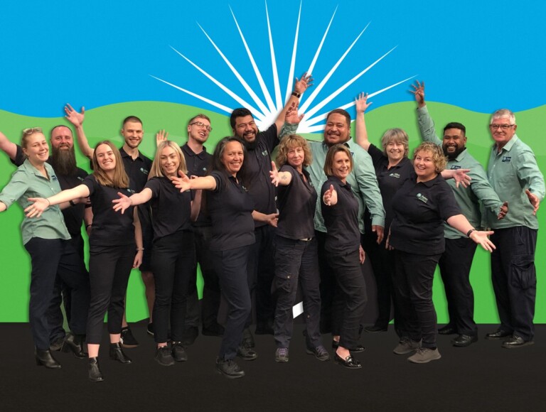 A group photo of the freedom mobility staff against a backdrop inspired by their logo. They've their hands thrown up in an excited gesture.