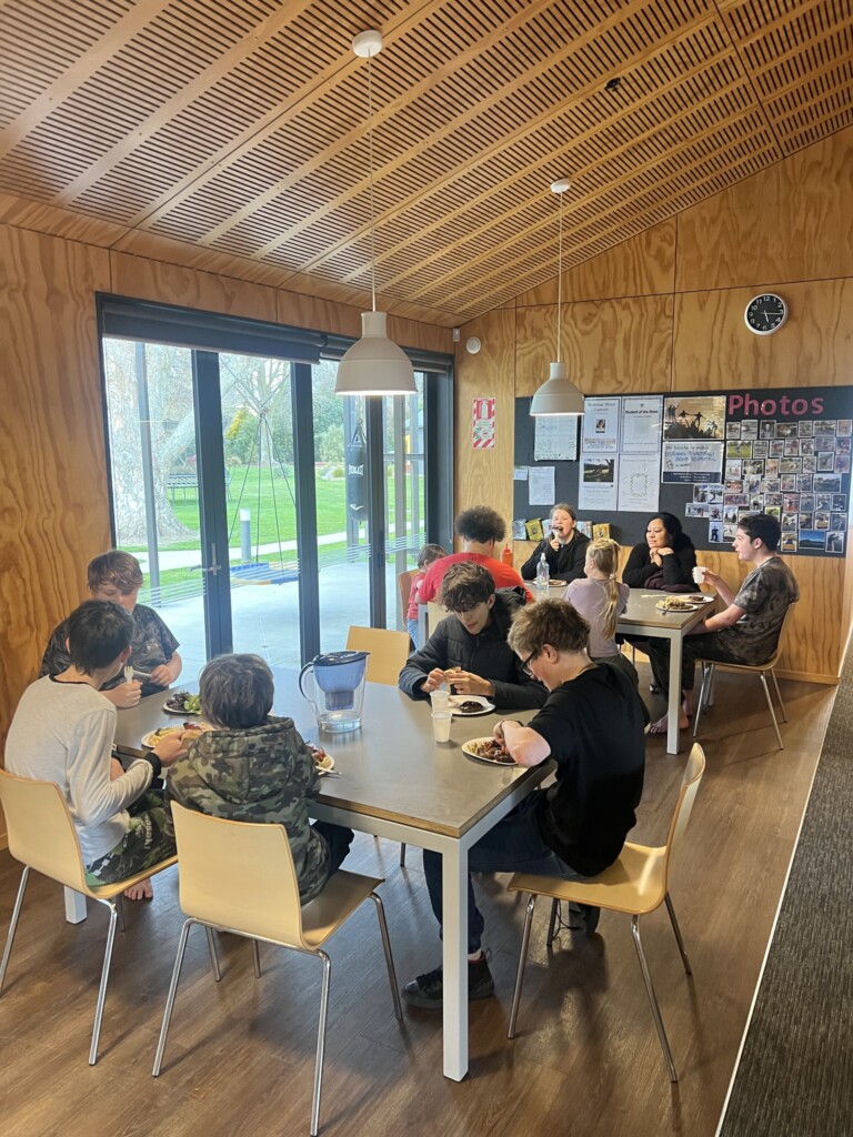 A photo of a group of people eating at various tables