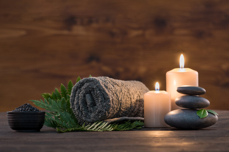 Towel on fern with candles and black hot stone on wooden background. Hot stone massage setting lit by candles. Massage therapy for one person with candle light. Beauty spa treatment and relax concept.; Shutterstock ID 732336370; Purchase Order: -